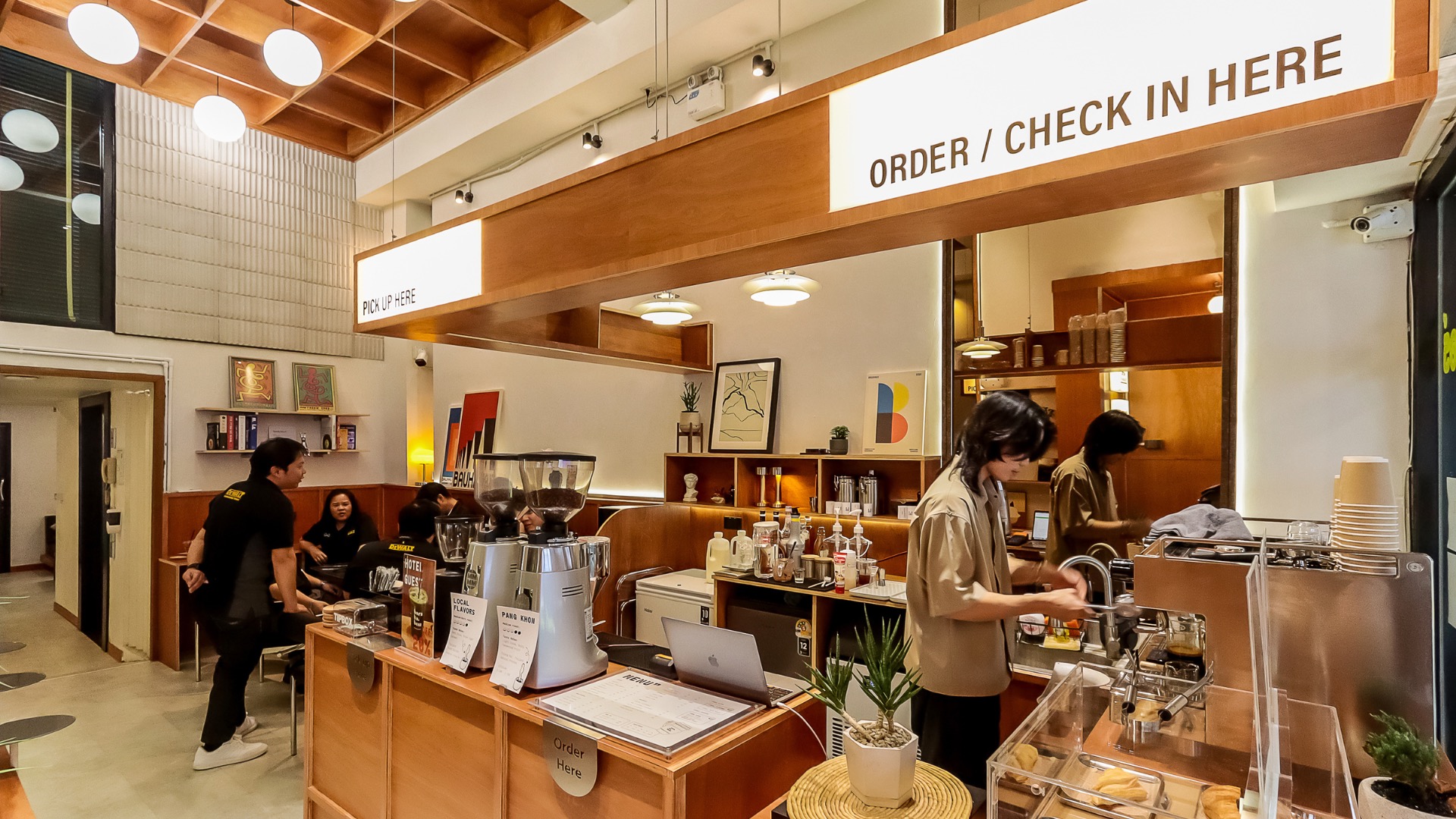 The Born to Bean cafe counter in the StayAt Bedever lobby, with baristas making coffee and an Order and Check In Here sign above