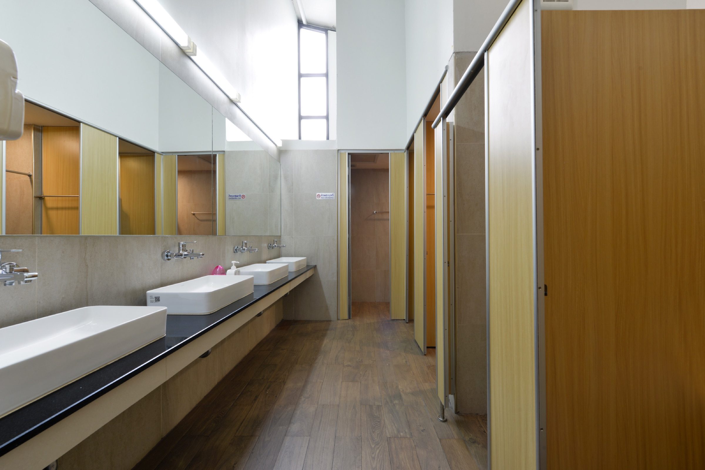 The gender-separated shared bathroom on the Loft floor at StayAt Bedever, with a row of vanities and private stalls